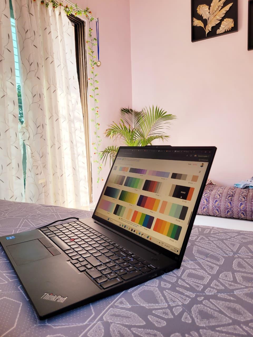 A laptop showing colour palettes on a bed in a sunlit room
